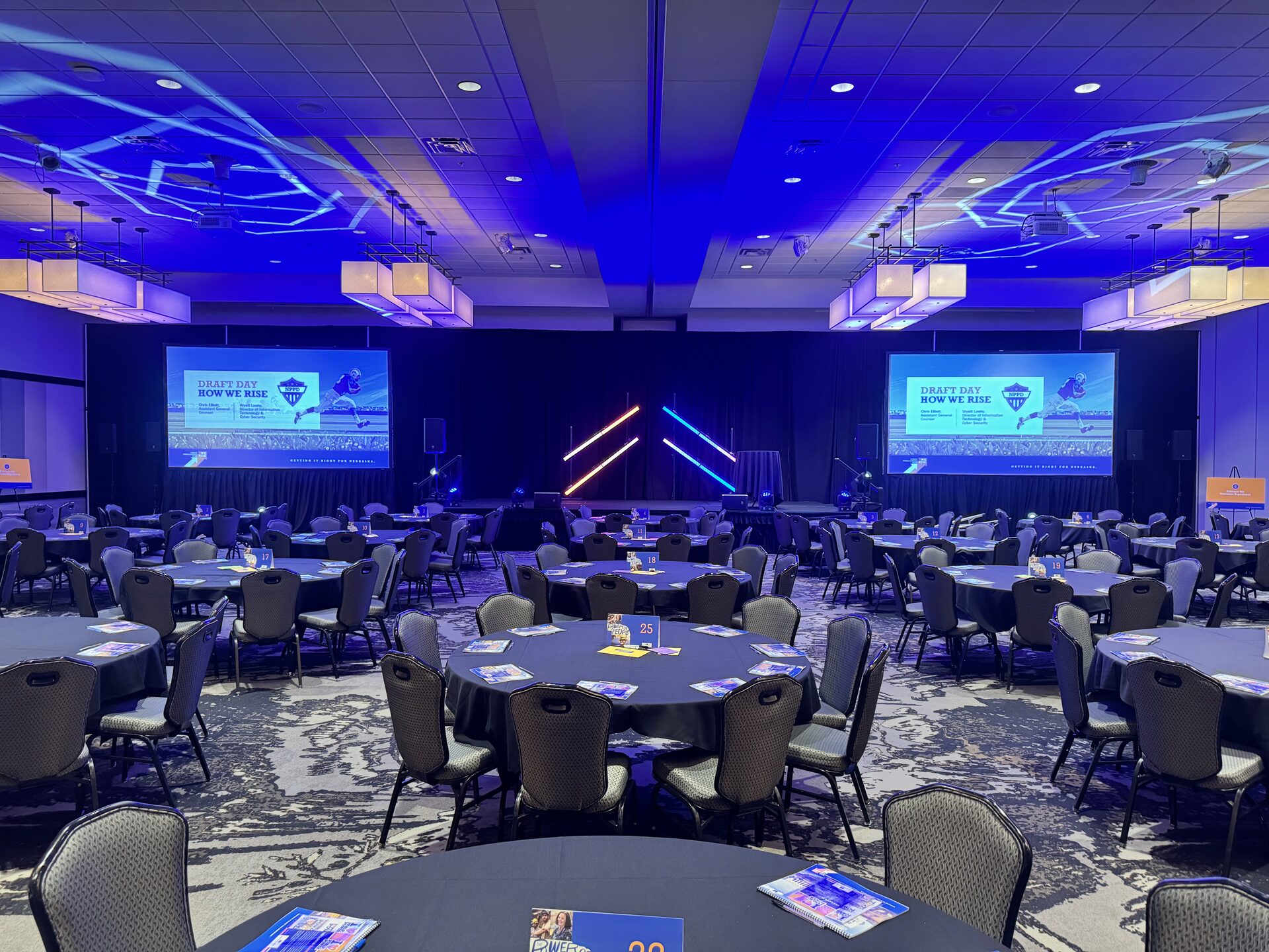 Corporate general session ballroom with dual screens, custom lighting and set pieces